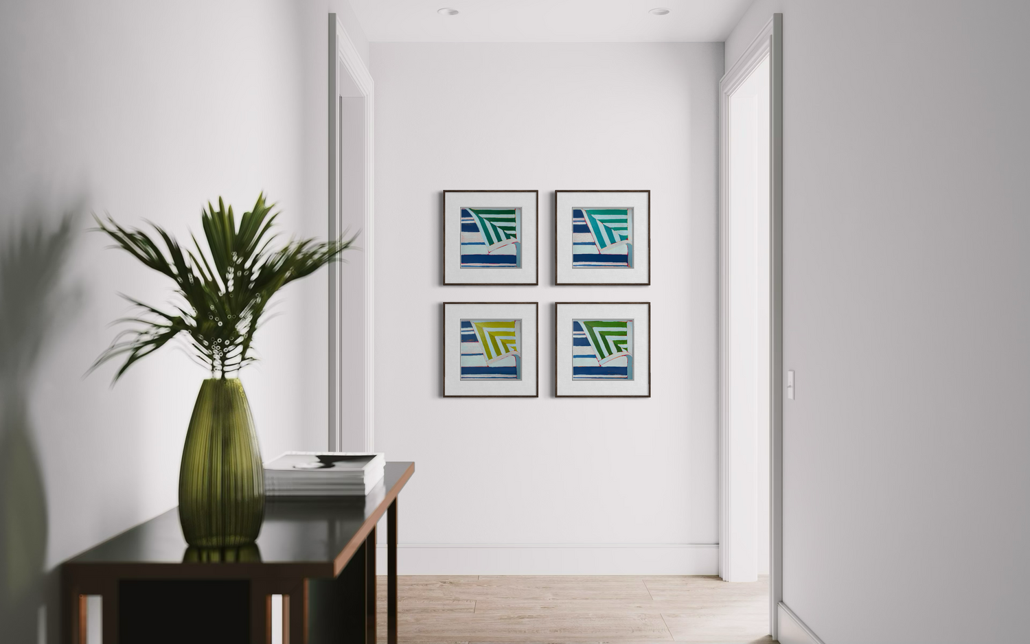Hallway wall with four framed colorful sailboat artworks, pale doors and walls, and a tall green vase on a console table.